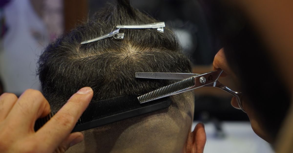 Kapper knipt met een uitdunschaar en kam het haar van een klant in een kapsalon