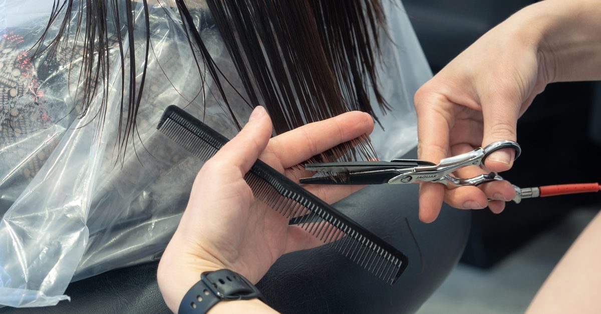 Kapper knipt met een schaar en kam het natte haar van een klant in een kapsalon