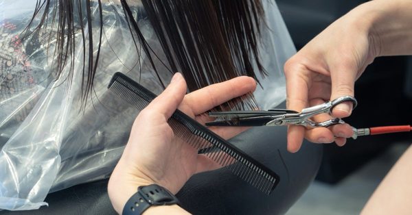 Kapper knipt met een schaar en kam het natte haar van een klant in een kapsalon