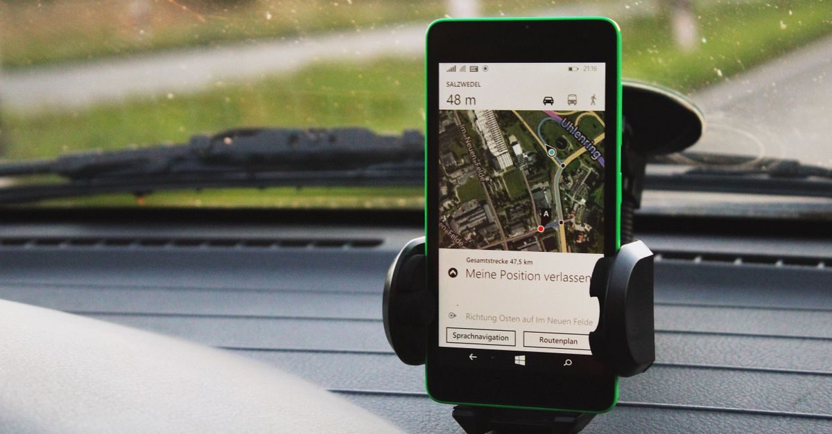 Smartphone fixé sur le tableau de bord d'une voiture affichant une application de navigation GPS avec une carte détaillée