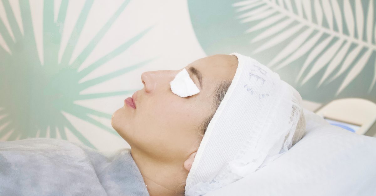 Cliente allongée en institut de beauté, les yeux couverts de cotons, recevant un soin du visage relaxant