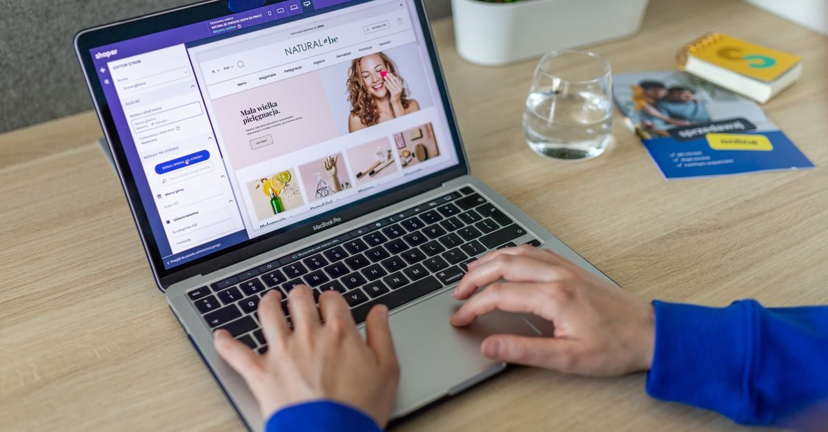 Person arbeitet an einem Laptop an der Gestaltung einer Website mit Produktbildern auf einem hellen Schreibtisch