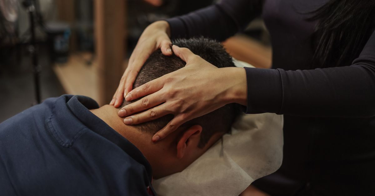 Terapeuta dando un masaje relajante en la cabeza a un hombre en un centro de bienestar con ambiente tranquilo