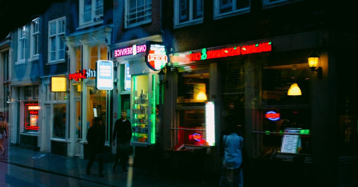 Verlichte winkelpuien en voorbijgangers in een donkere stadstraat bij avondlicht
