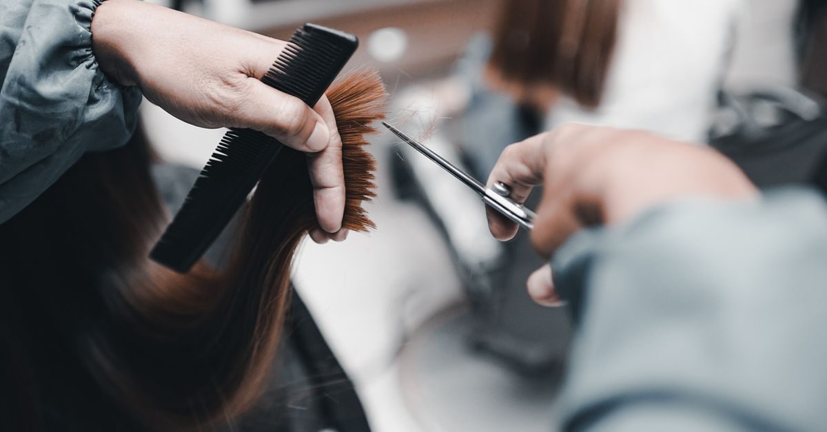Peluquero corta el cabello de una clienta con tijeras y un peine en un salón de belleza con enfoque profesional