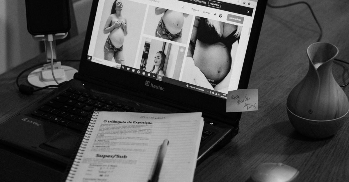 Laptop mit Schwangerschaftsfotos auf dem Bildschirm, Notizblock und Diffusor auf einem Schreibtisch in Schwarz-Weiß