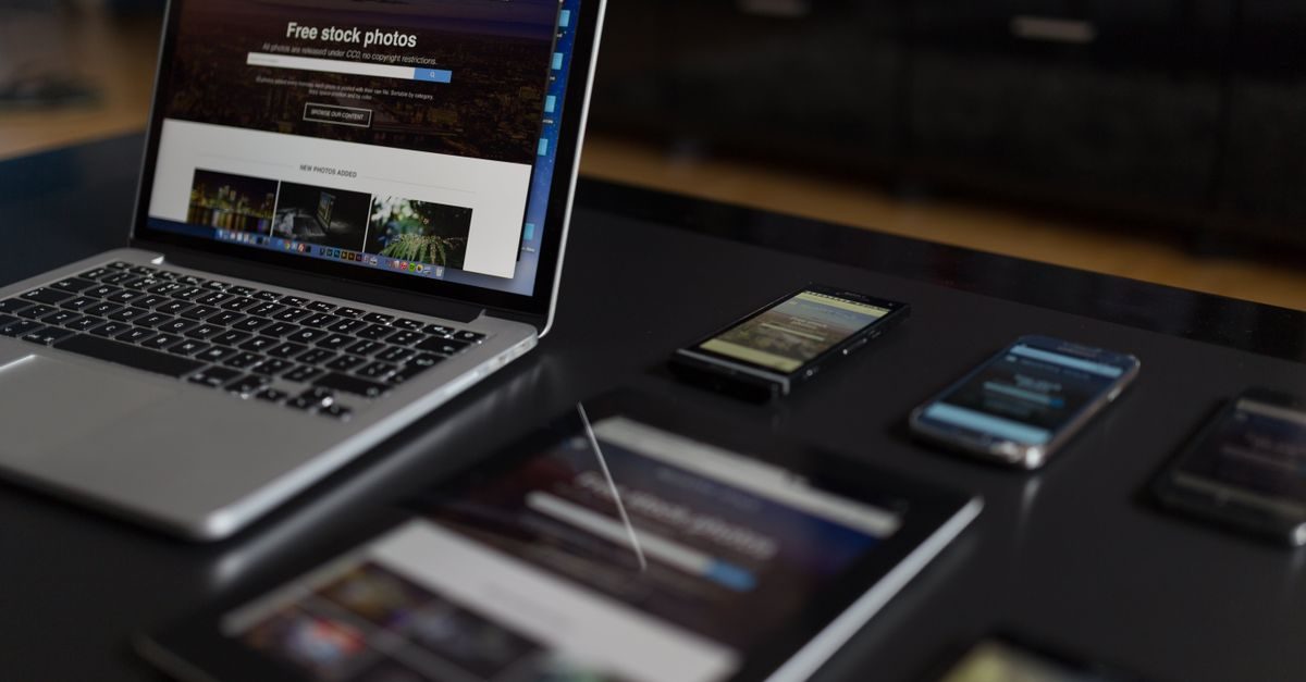 Laptop, tablet en meerdere smartphones op een donkere tafel met websites voor stockfoto's in beeld
