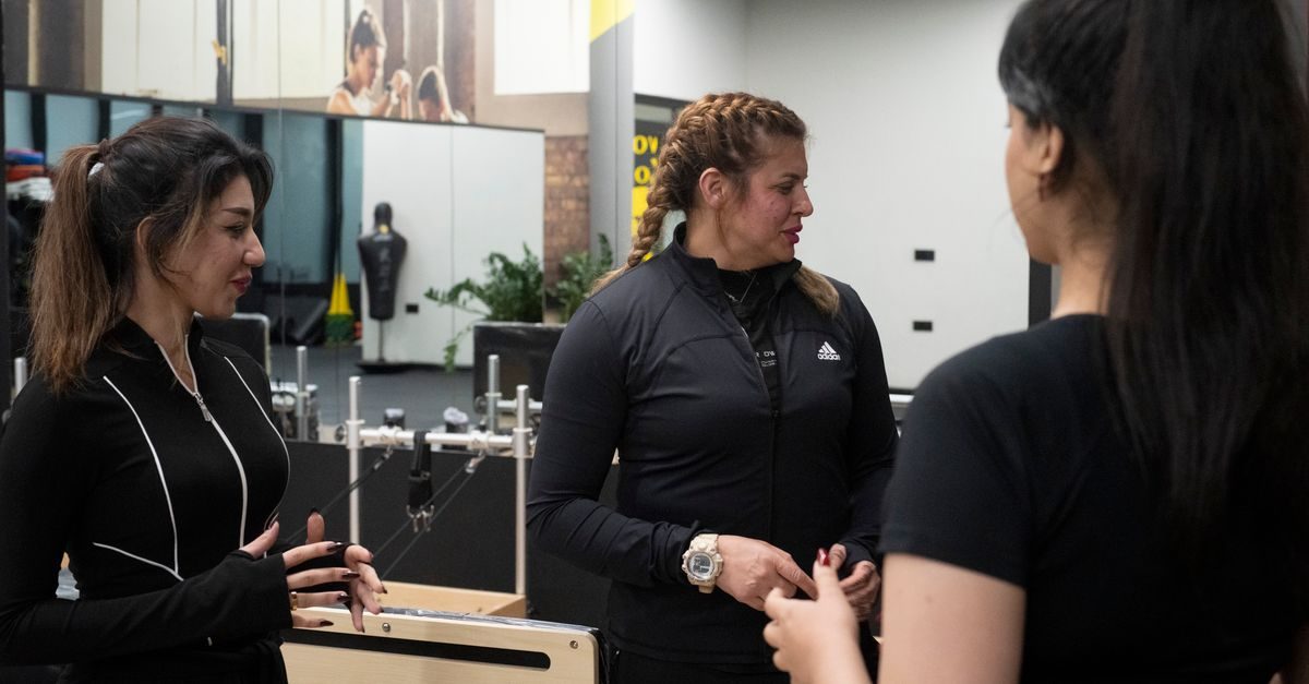 Drie vrouwen in sportkleding in gesprek met elkaar in een moderne sportschool