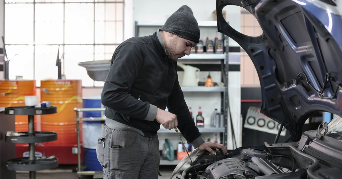 Un mécanicien en bonnet vérifie le niveau d'huile d'une voiture dans un garage automobile bien éclairé
