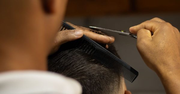 Kapper knipt met een schaar en kam het haar van een klant in een professionele setting