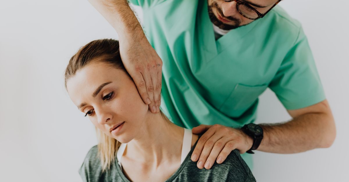 Fisioterapeuta con uniforme verde realiza un ajuste cervical a una paciente en un entorno clínico profesional y tranquilo