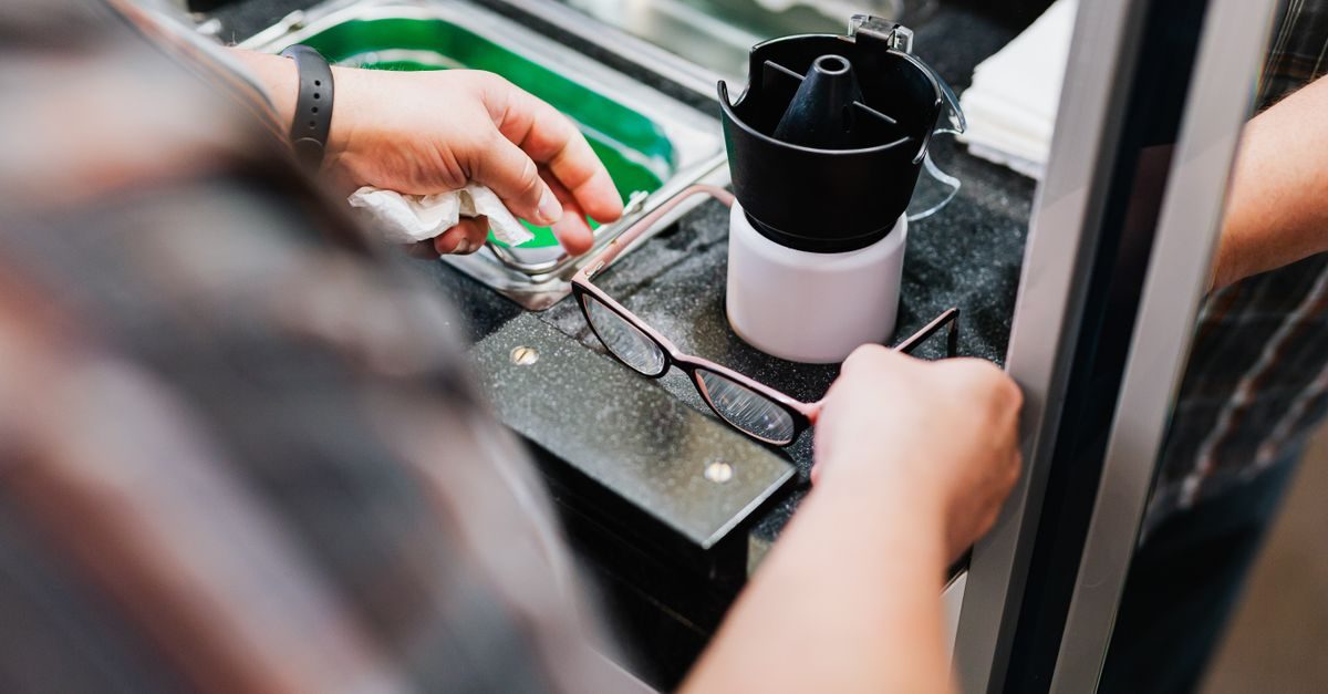 Optiker reinigt eine Brille an einer professionellen Reinigungsstation mit einem Ultraschallgerät