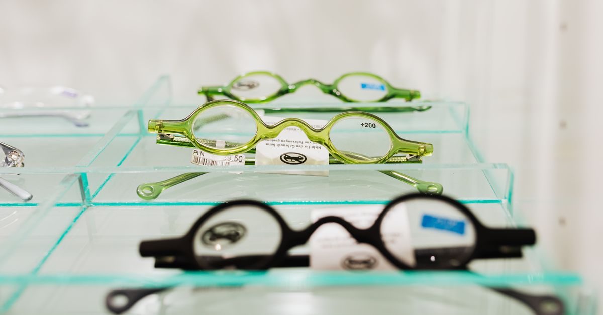 Groene en zwarte leesbrillen met ronde glazen op glazen schappen in een winkel