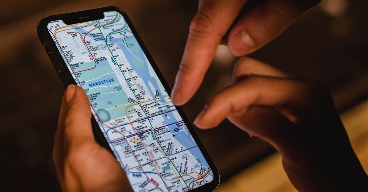 Manos sostienen un teléfono móvil que muestra un mapa detallado del metro de Manhattan mientras un dedo señala la pantalla
