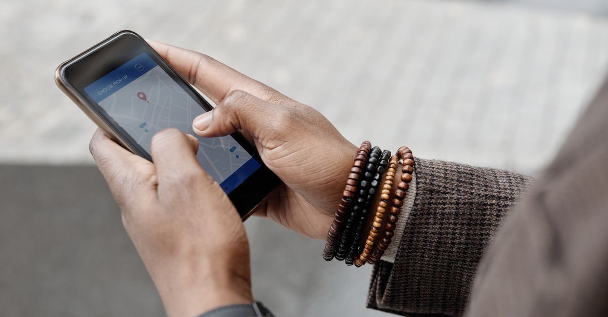 Person mit Armbändern bedient ein Smartphone mit einer Karten-App zur Standortsuche im Freien
