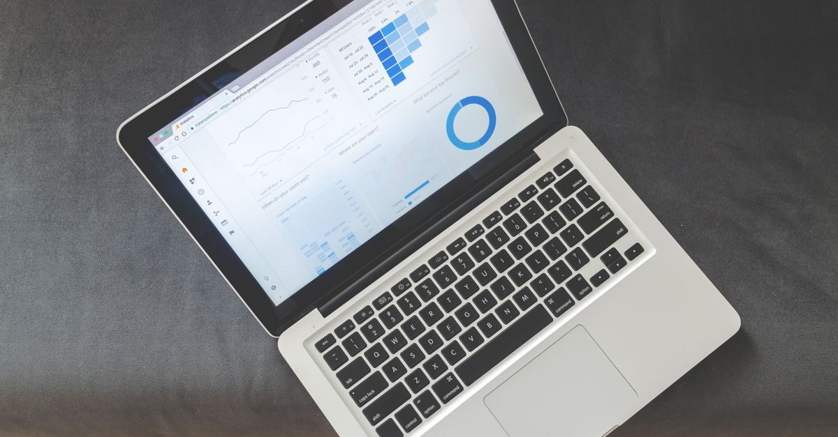 Laptop op een grijze ondergrond met een scherm vol grafieken en data-analyse