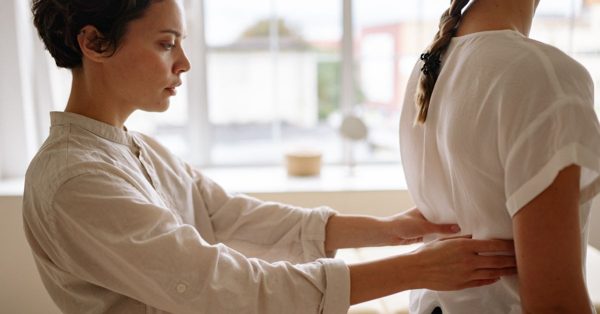 A focused physiotherapist examines a patient's back in a bright, professional clinic setting