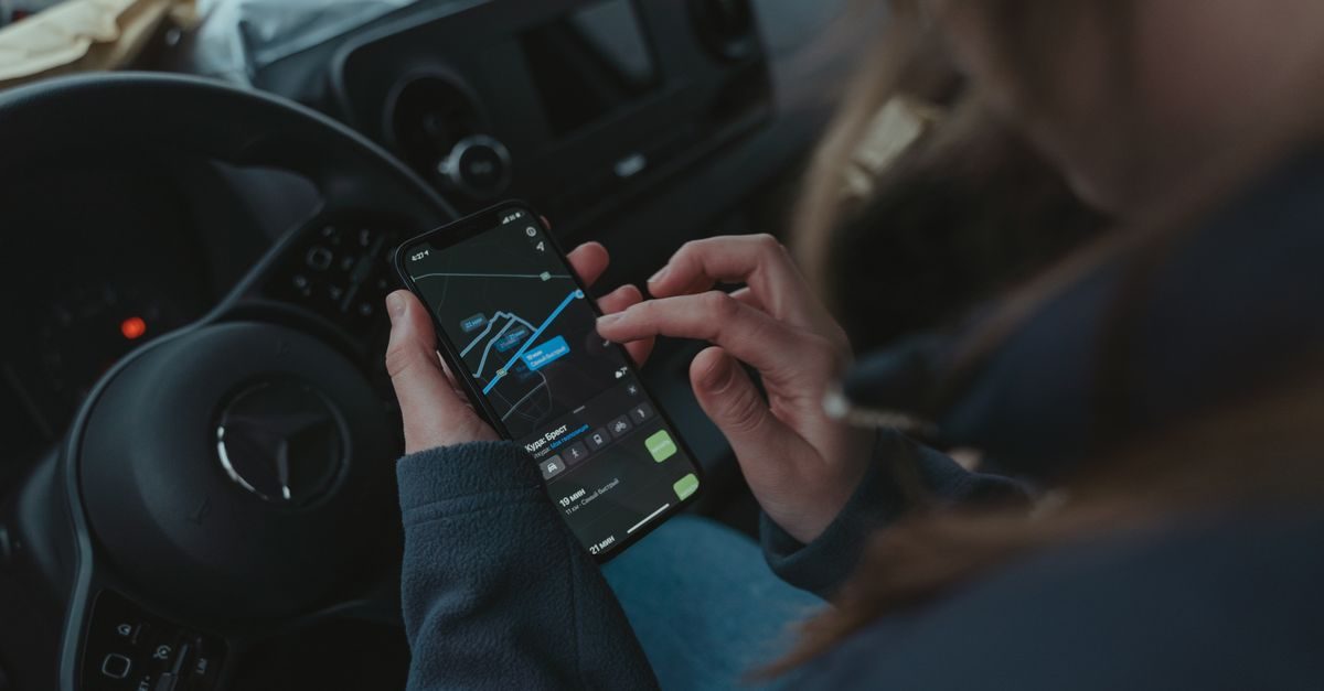 Une personne utilise une application de navigation GPS sur son smartphone au volant d'une voiture