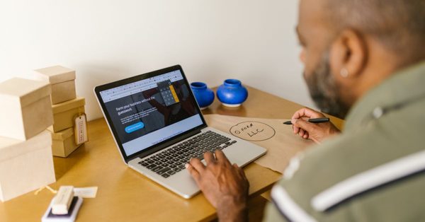 Un homme travaille sur son ordinateur portable à un bureau avec des boîtes en carton et des notes manuscrites