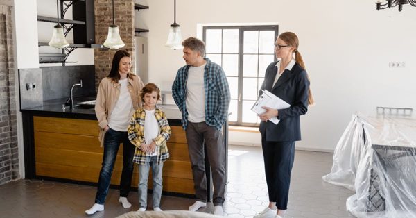 Fastighetsmäklare visar upp ett modernt kök för en familj med ett barn i en ljus och öppen bostad
