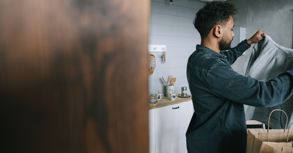 Un homme déballe ses vêtements dans une chambre d'hôtel moderne et lumineuse à l'ambiance sereine