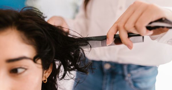 Kapper kamt het donkere haar van een klant in een professionele salonsetting