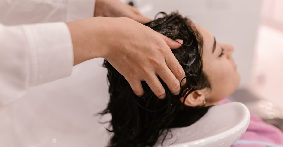 Eine Friseurin wäscht einer Kundin entspannt die Haare in einem Waschbecken in einem hellen Salon
