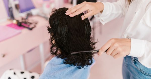 Kapper kamt het donkere haar van een klant in een roze salon met een ontspannen sfeer
