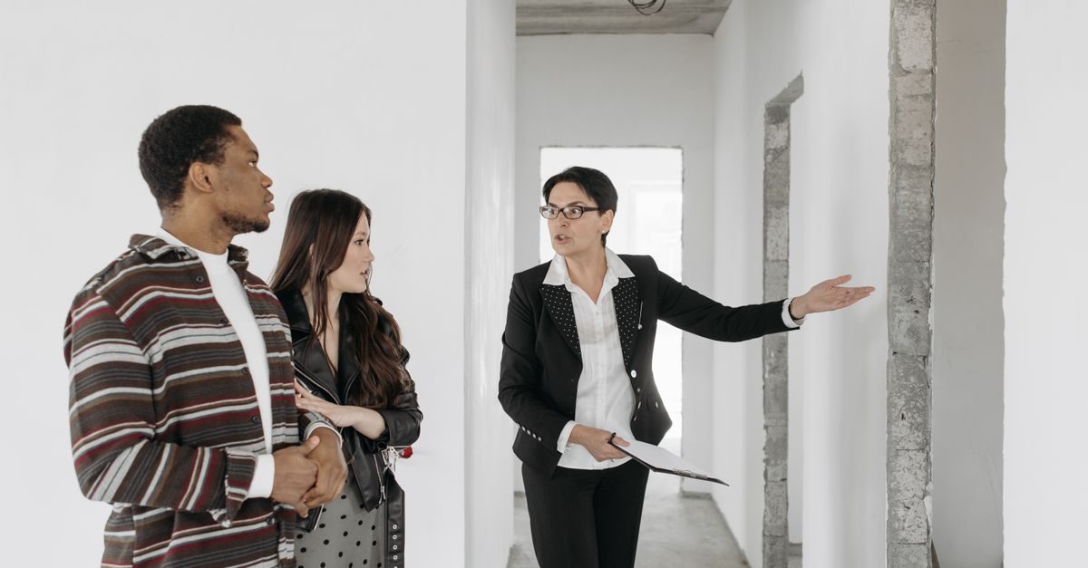 Agente inmobiliaria muestra una vivienda en construcción a una pareja joven interesada en comprar