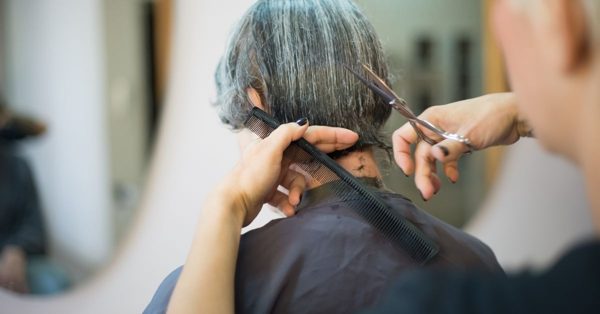 Kapper knipt het grijze haar van een klant met een schaar en kam in een professionele salon