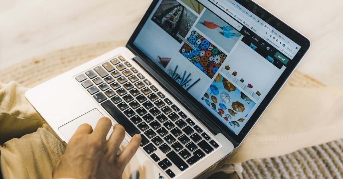Persona che usa un computer portatile per navigare su un sito web con una galleria di immagini su sfondo chiaro